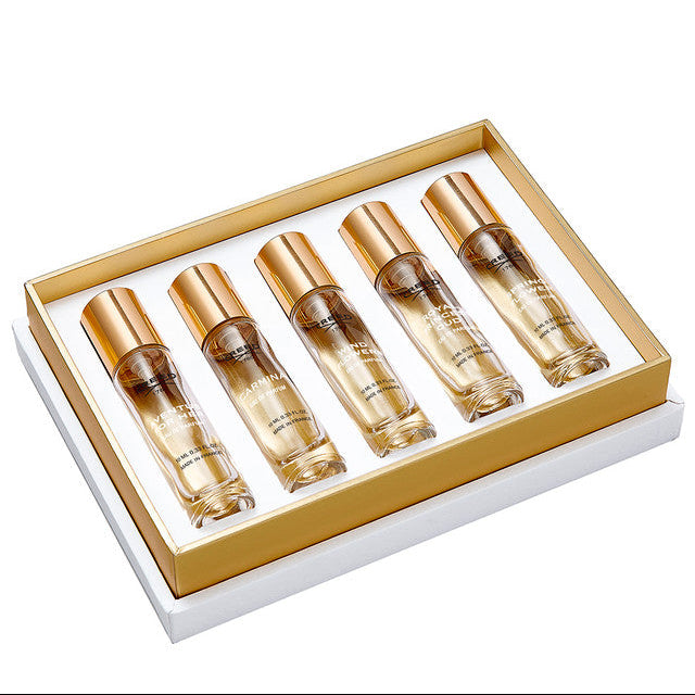 Set of five perfume bottles in a gold and white box on a white background